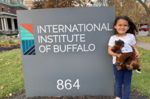 kid with a stuffed Buffalo standing in front of an IIB sign.